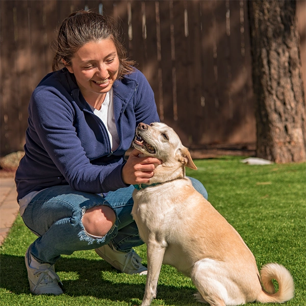 A woman enjoying her time in with her dog her backyard in Prescott AZ. She has more time for hiking and to enjoy her pup because Clickapro is taking care of the dog poop removal.